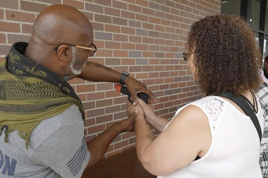 An instructor guiding a student's grip during firearms training